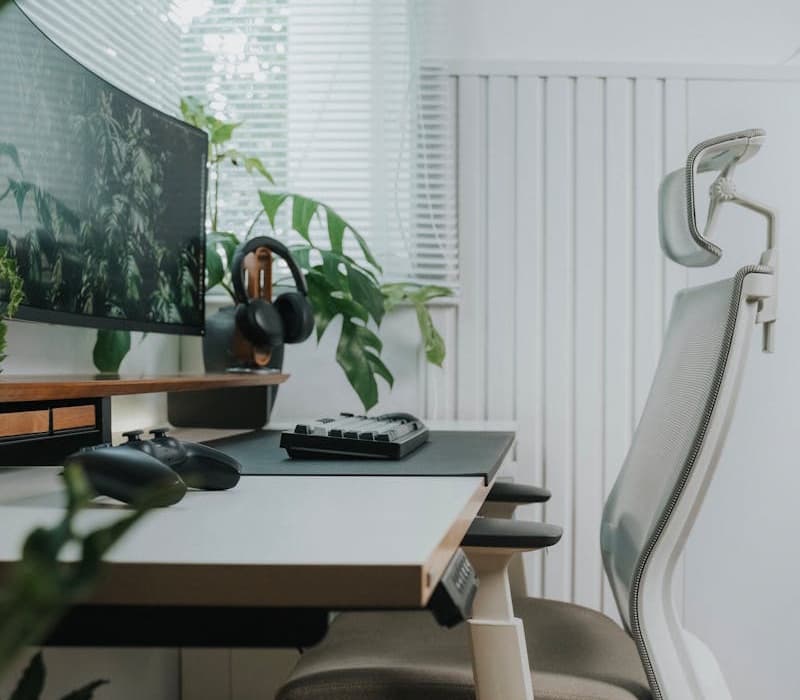 Image of a clean standing desk with a single ultrawide display, a compact keyboard, and a chair