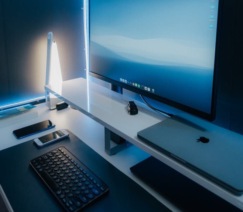 Image of a tidy desk with a laptop, 32 4K monitor, external keyboard, and soft blue lighting