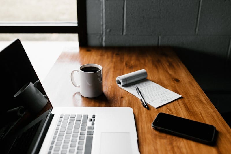 Image of a minimalist desk with a coffee and an open laptop